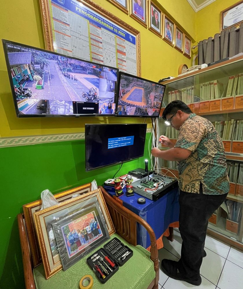 Teknisi memeriksa perangkat CCTV dan monitor